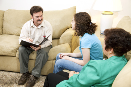 Caring family therapist counseling a teenage girl and her mother.